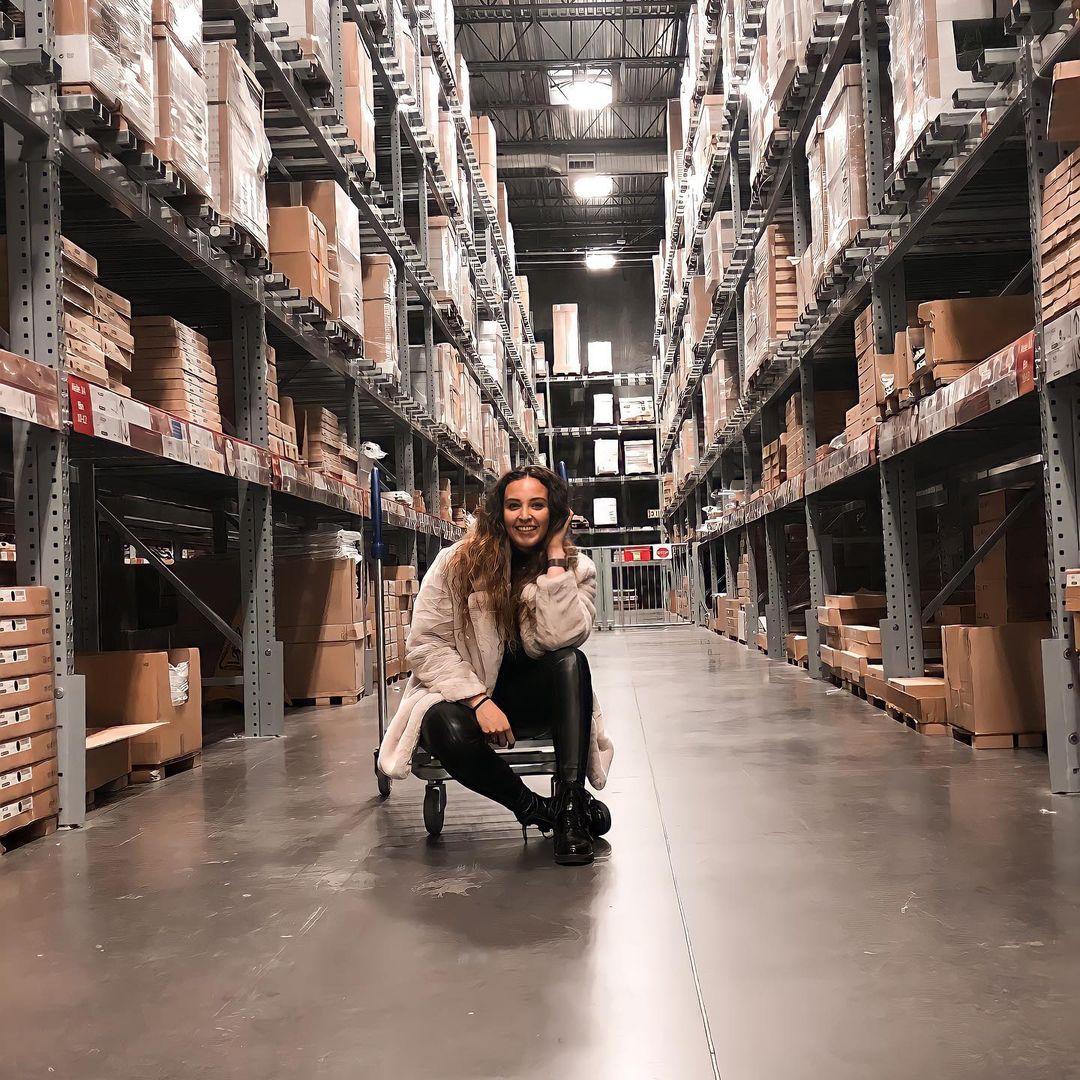 a woman sitting on a cart in the Ikea warehouse