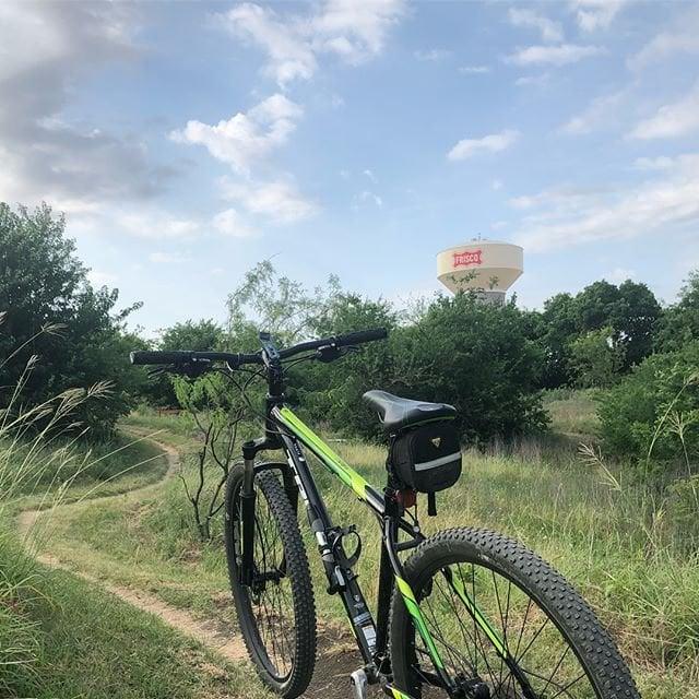 a bike parked on a path in front of the Frisco water tower