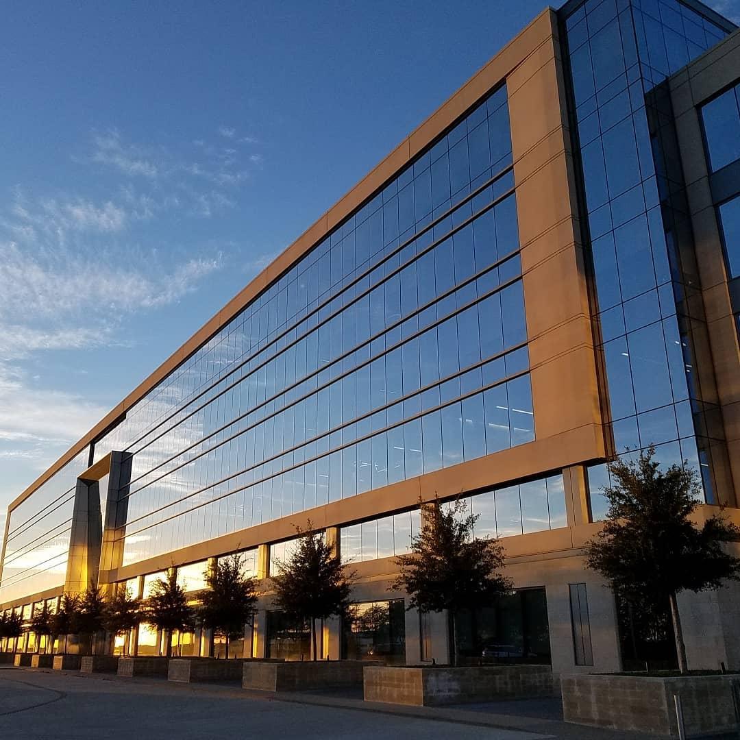 a glass building with the reflection of the sky