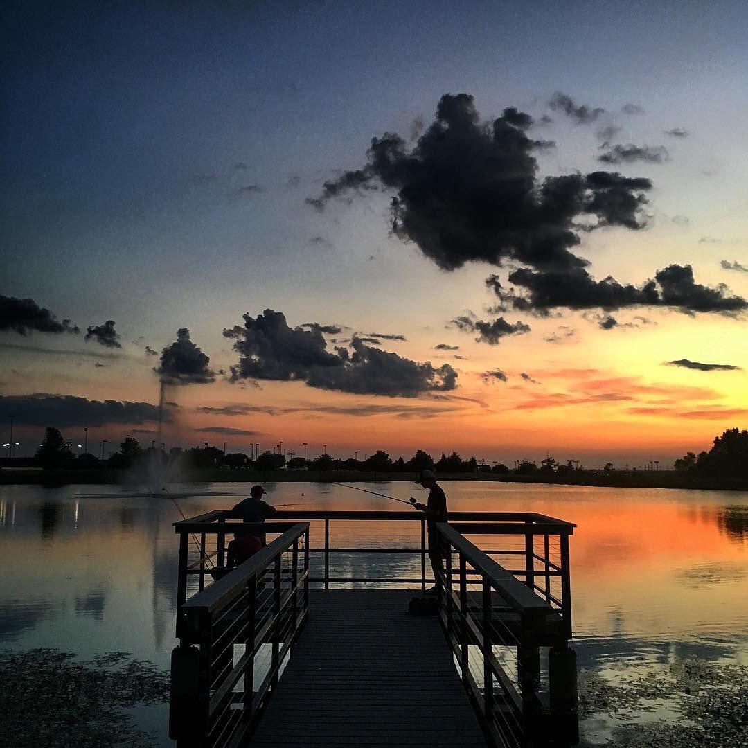 people fishing off a dock during sunset