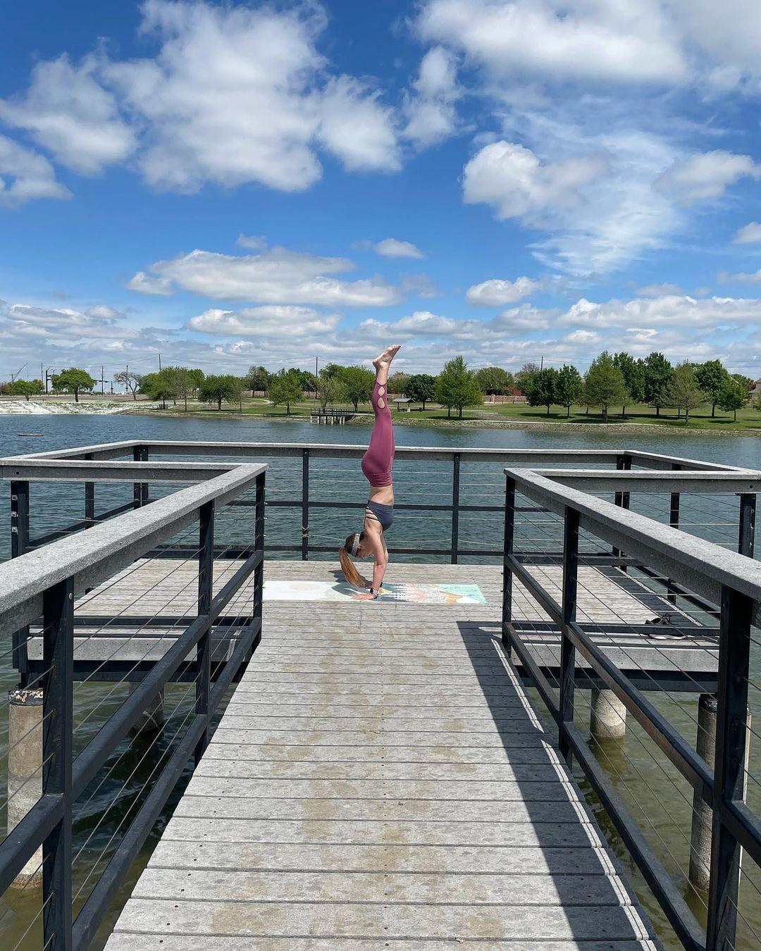 a woman doing a handstand on a dock